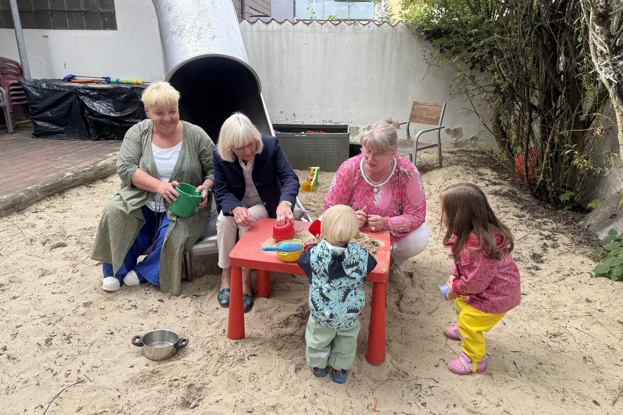 drei Frauen beim Spielen mit Kindern im Sandkasten